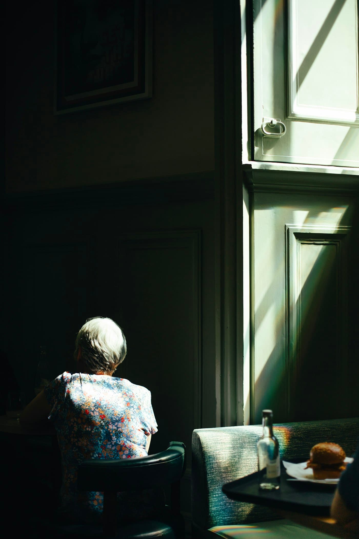 An elder sitting peacefully by a sunlit window at home