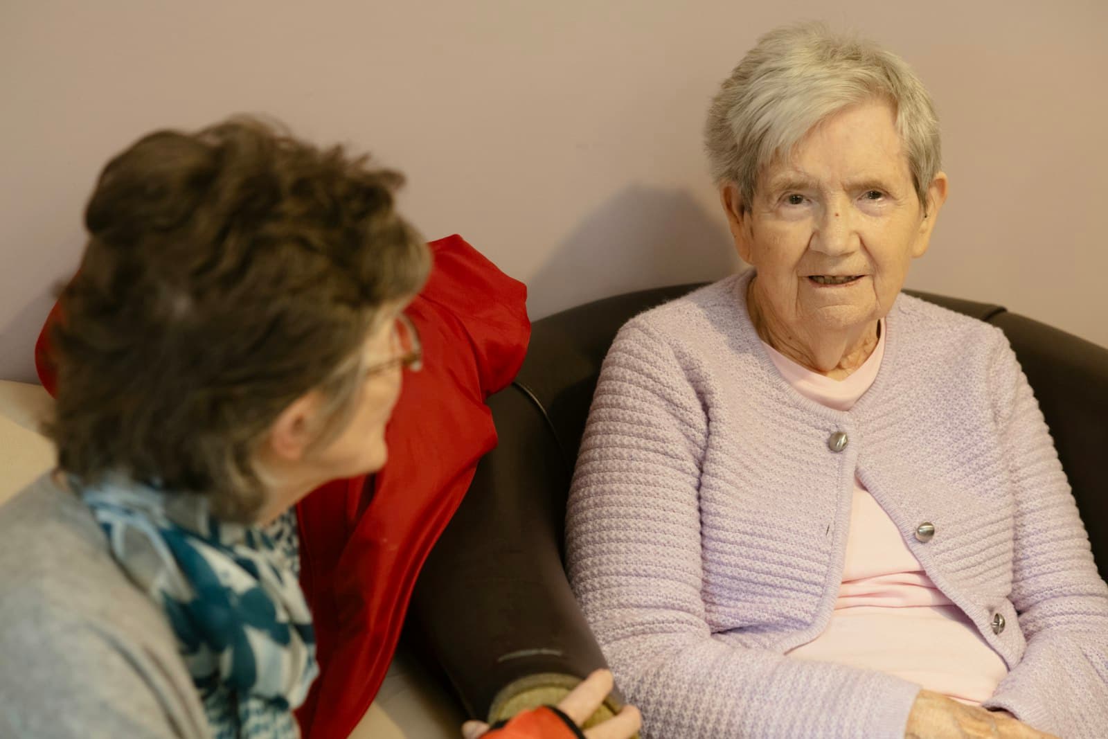 Two elder companions sharing a warm conversation at home